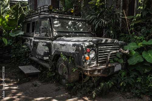Fotografia Old broken dirty military jeep crashed into a tree in jungle tropical trees and