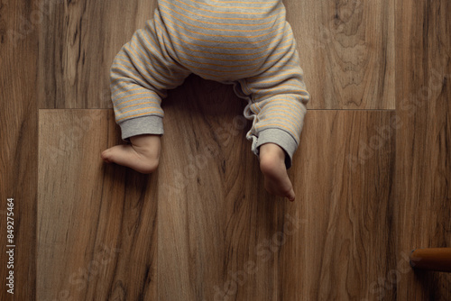 Fotografie baby crawling on a parquet board or laminate, 0-1 year old baby skills