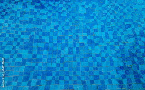 Top view space of clear water surface is rippling on swimming pool, blue grid mosaic tiles background. Empty space at poolside on sunny day, summer background poster concept.