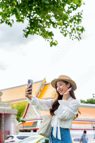 Photography Asian chinese female tourist using phone in front a famous landmark in Bangkok,