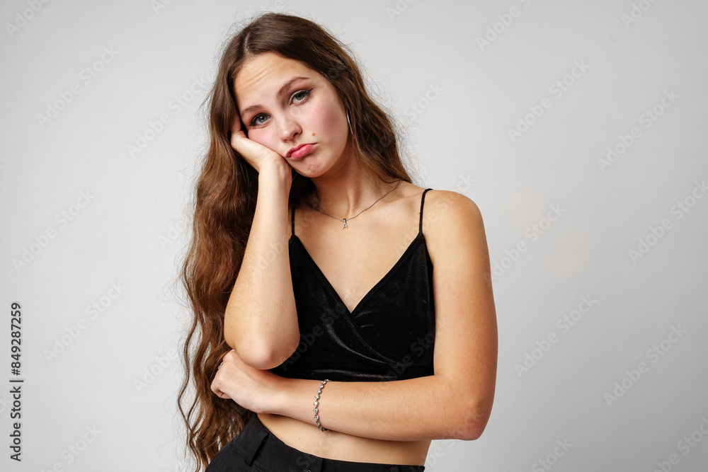 Young Woman Expressing Boredom With Hand on Face Against Neutral Background Young Woman Expressing Boredom With Hand on Face Against Neutral Background