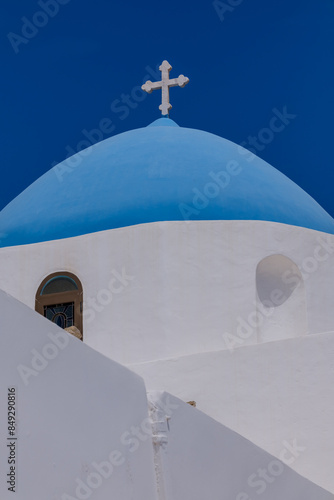 A cross on the top of an orthodox whitewashed church in Ios Greece and a blue sky in the background in Ios Greece