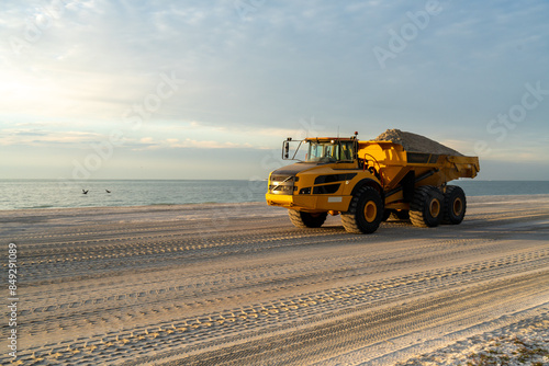 A loaded articulated hauler mining type dump truck carrying sand for a restoration project on a beach, Sanibel Island, Florida