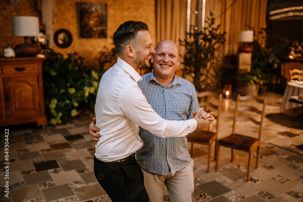 Valmiera, Latvia - September 9, 2023 - Two men dancing and laughing together indoors at a festive event, creating a joyful and heartwarming atmosphere. Valmiera, Latvia - September 9, 2023 - Two men dancing and laughing together indoors at a festive event, creating a joyful and heartwarming atmosphere.