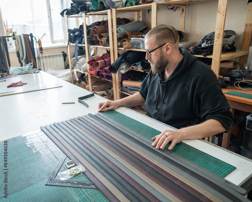 Leatherworker making leather belts in workshop. Leatherworker making leather belts in workshop.