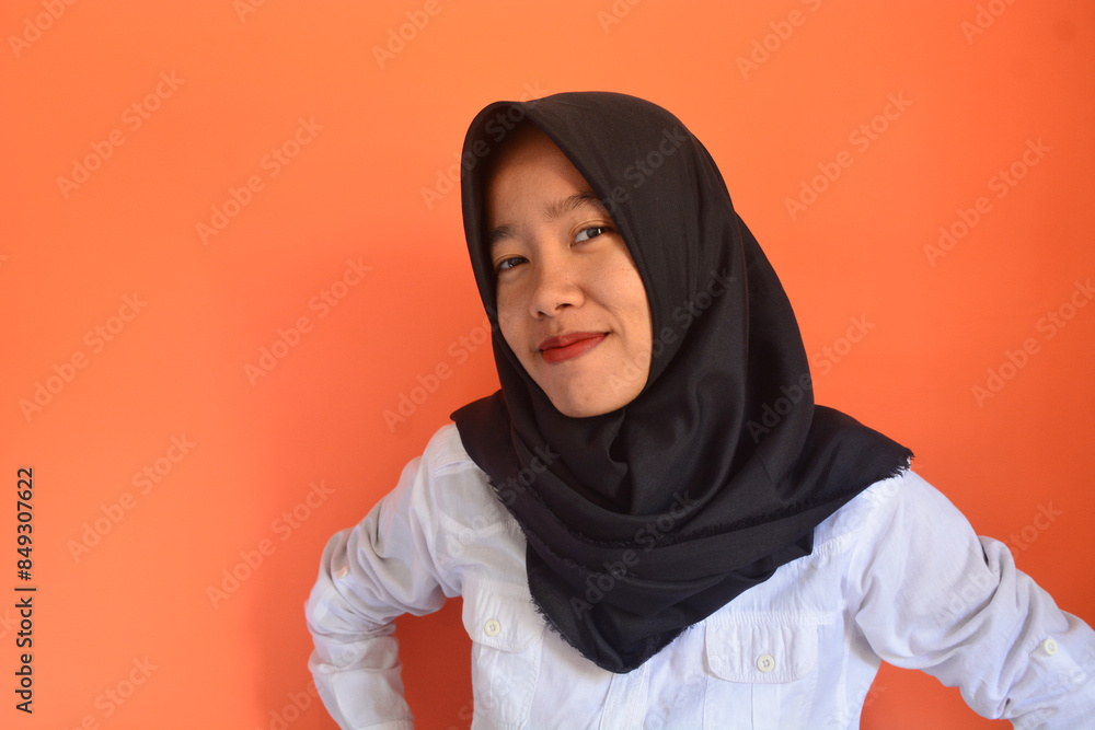 A Muslim Asian woman wearing a white shirt and black hijab is standing with a confident digital gesture giving coaching A Muslim Asian woman wearing a white shirt and black hijab is standing with a confident digital gesture giving coaching