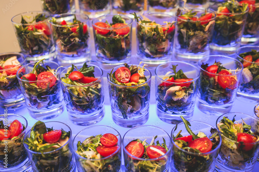 Fototapeta premium Beautifully decorated banquet catering table, with variety of with different food snacks appetizers on corporate birthday party event or wedding celebration, canape, salad, delicatessen setting