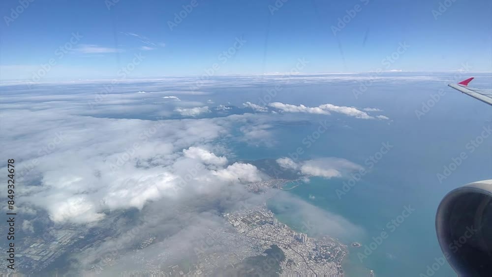 Aerial view of fluffy white clouds against a clear blue sky from an airplane window Aerial view of fluffy white clouds against a clear blue sky from an airplane window