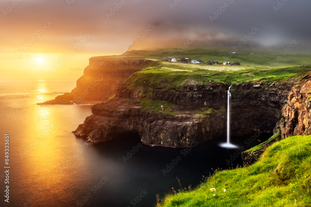 Mulafossur waterfall on sunset time. Dramatic sky with golden light. Gasadalur village, Vagar Island, Faroe Islands, Denmark. Landscape photography Mulafossur waterfall on sunset time. Dramatic sky with golden light. Gasadalur village, Vagar Island, Faroe Islands, Denmark. Landscape photography