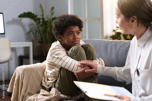 Fotografie Portrait of young African American boy listening to caring psychologist in thera