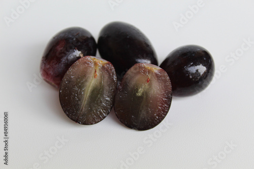 Halved seedless black grape, off the stem, without stalk, isolated on white background photo