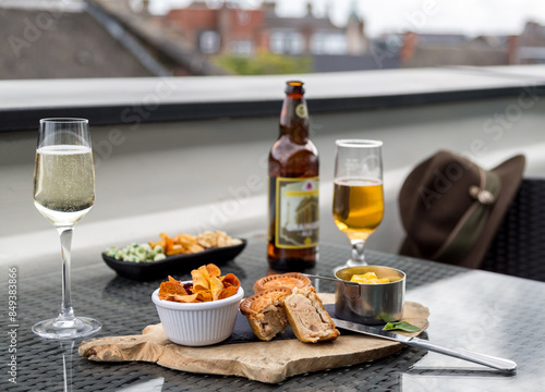 Tableau sur toile Some bar snacks consisting of mini pork pies, vegetable crisps or chips served with a cold beer and a glass of sparkling wine
