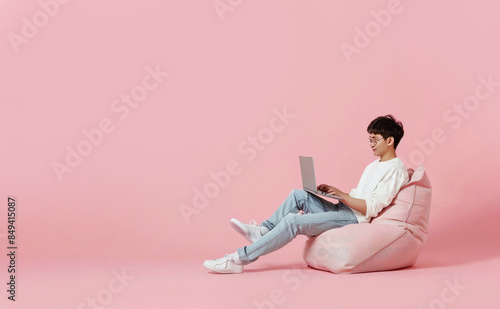 Full body young happy young man of Asian ethnicity sit in bag ch photo