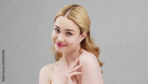 Portrait of a charming sensual blonde woman on a light background, illustrating a cosmetology concept. A close-up of a half-naked woman in a studio showing off her natural beauty and flawless skin.