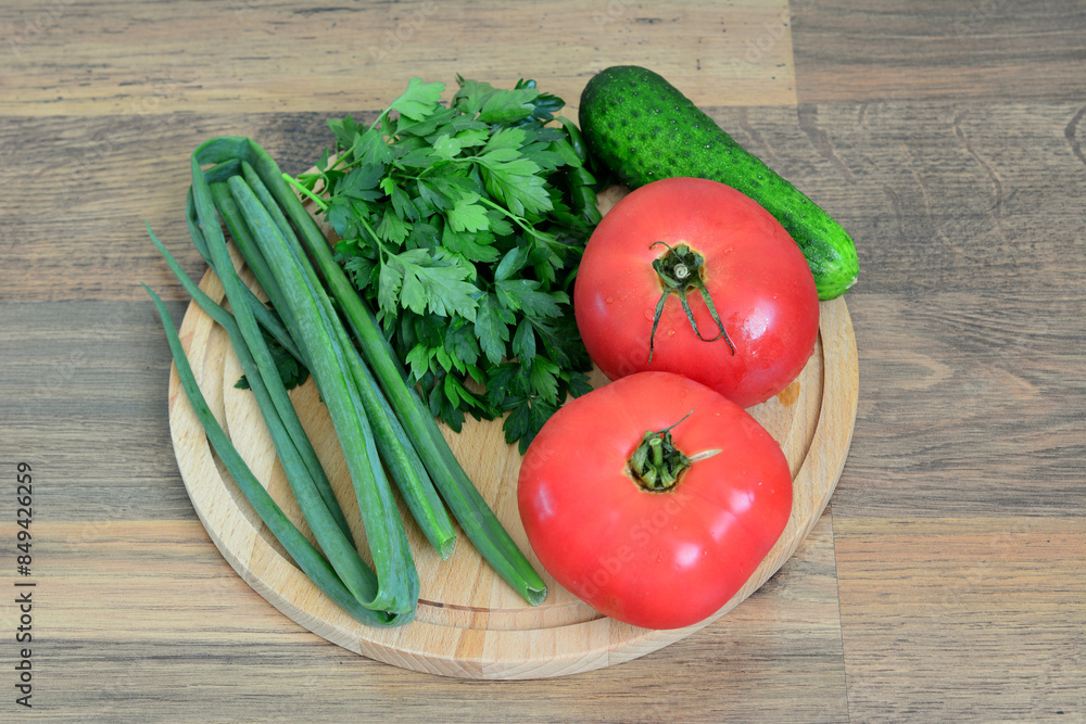 a wooden tray with a bunch of vegetables including tomato, parsley and cucumber a wooden tray with a bunch of vegetables including tomato, parsley and cucumber