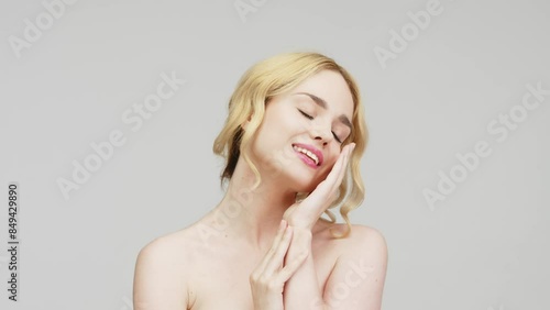 Portrait of a charming sensual blonde woman on a light background, illustrating a cosmetology concept. A close-up of a half-naked woman in a studio showing off her natural beauty and flawless skin.