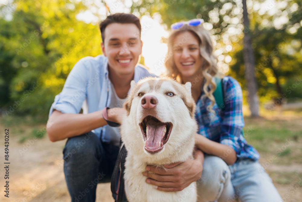 funny young stylish couple playing with dog in park funny young stylish couple playing with dog in park
