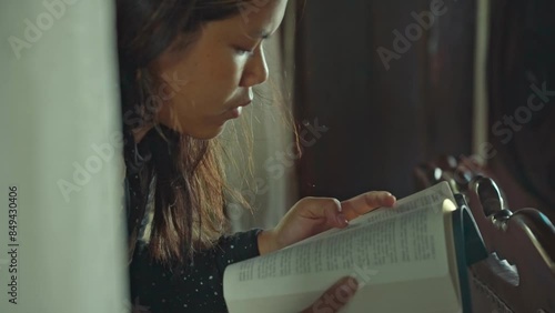 asian woman reading the Christian bible book on wooden table vintage room