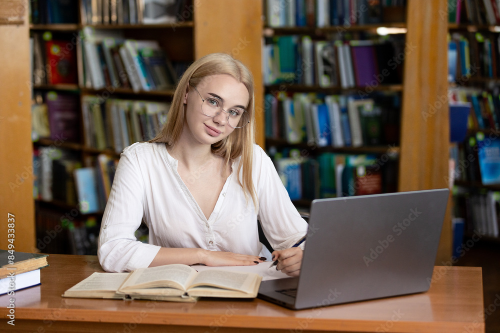 A young teenage girl in the library writes an essay or outline, taking diligent notes. This scene embodies the concepts of passing exams, studying, and education, highlighting her dedication to academ A young teenage girl in the library writes an essay or outline, taking diligent notes. This scene embodies the concepts of passing exams, studying, and education, highlighting her dedication to academ