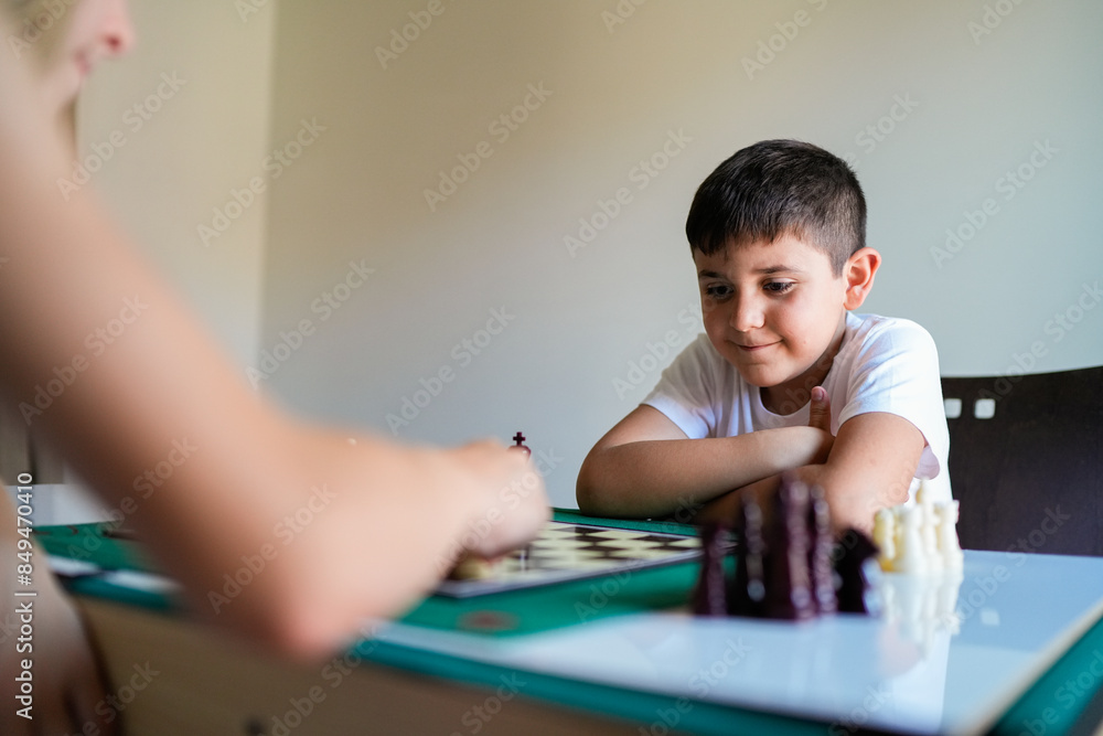 A boy is playing chess with another person A boy is playing chess with another person