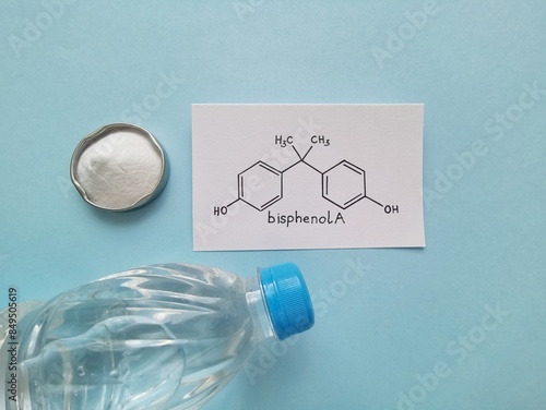 Structural chemical formula of bisphenol A with white bisphenol A powder and plastic bottle. Bisphenol A is a chemical compound used in the manufacturing of various plastics.