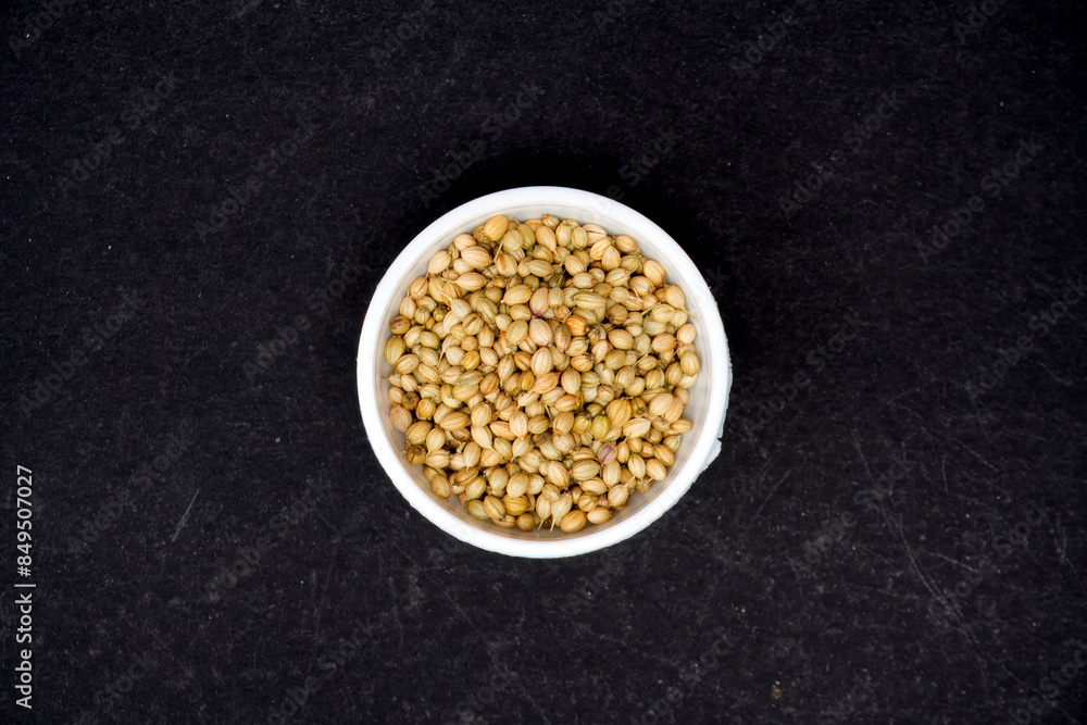 top view of Dried coriander seeds in white bowl, isolated in black background top view of Dried coriander seeds in white bowl, isolated in black background