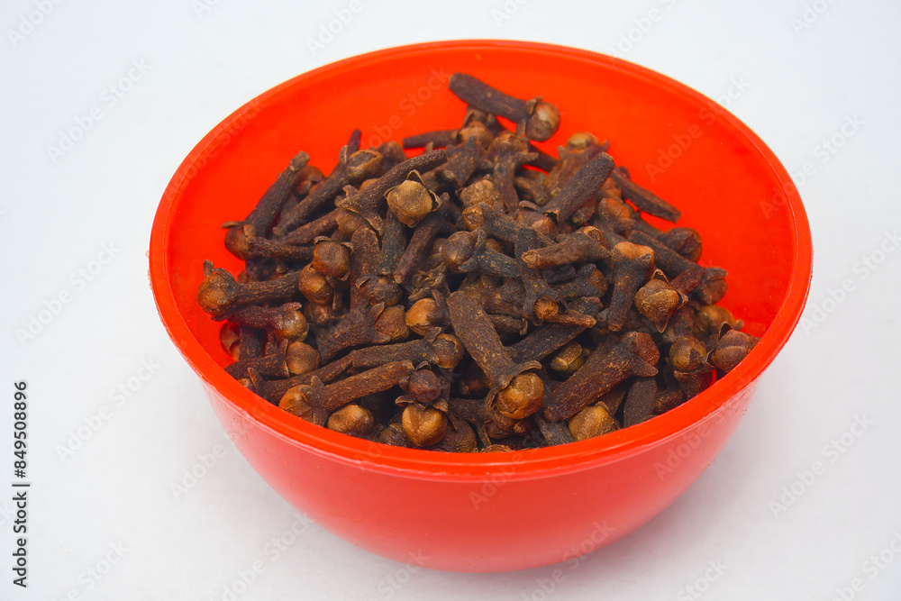 freshly dried cloves in red bowl. Dried cloves are a multipurpose plant that may be used as a natural medicine and to flavor cuisine. Natural Dry Clove Spice. isolated in white background freshly dried cloves in red bowl. Dried cloves are a multipurpose plant that may be used as a natural medicine and to flavor cuisine. Natural Dry Clove Spice. isolated in white background