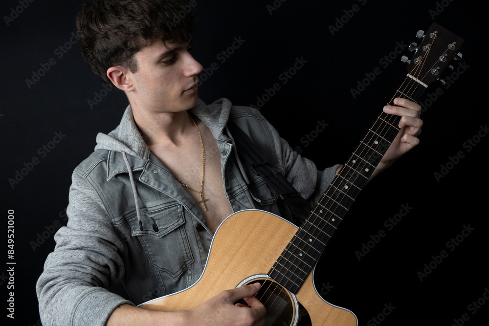 Obraz premium Shirtless young man in denim jacket playing guitar in photo studio