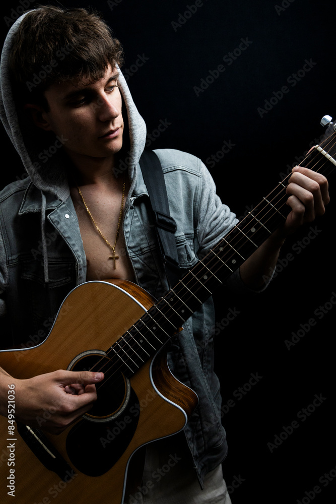 Obraz premium Shirtless young man in denim jacket playing guitar in photo studio