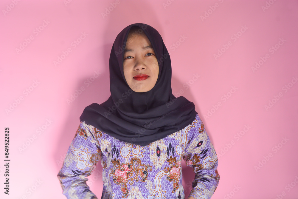 Close up photo of beautiful cheerful Asian Muslim woman, with hand gesture pointing at empty space isolated on pink background Close up photo of beautiful cheerful Asian Muslim woman, with hand gesture pointing at empty space isolated on pink background