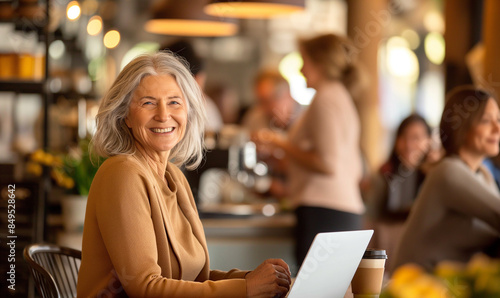 Senior Woman Enjoying Coffee and Working on Laptop in a Cozy Cafe