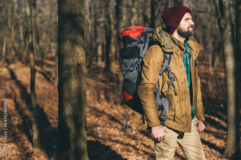young hipster man traveling with backpack in spring autumn forest
