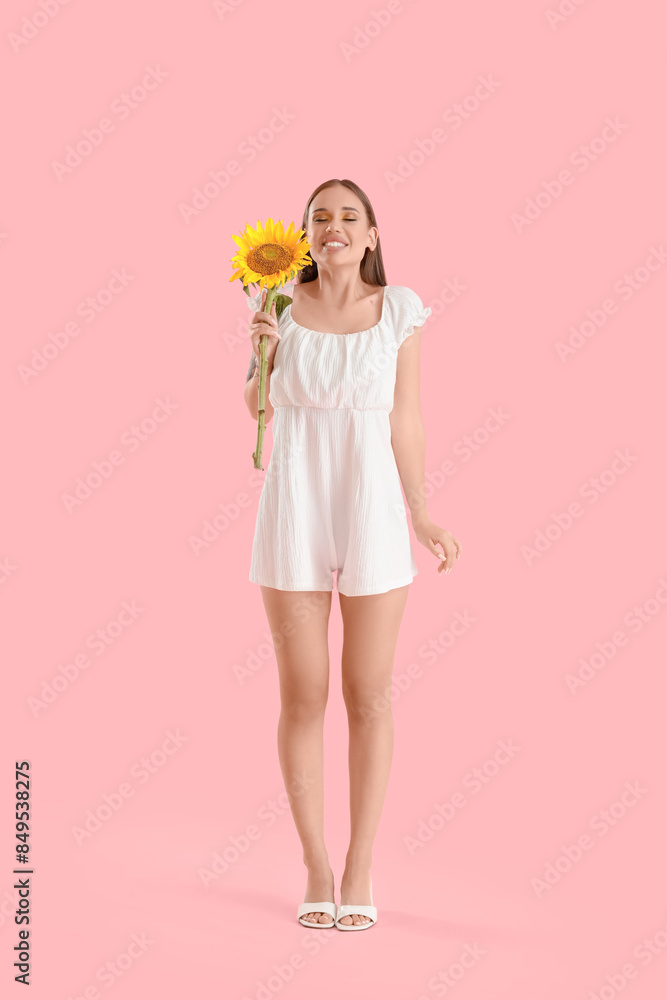 Young happy woman with beautiful sunflower on pink background Young happy woman with beautiful sunflower on pink background