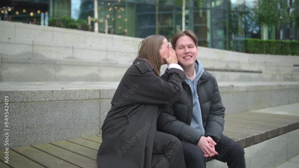 handsome man laughing at a joke his friend told him. They are sitting on a concrete bench and there is a lot of green. Concept: Man laughing, relationship, two colleagues