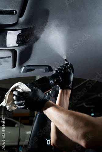 Detailing car headliner covering. Spraying detergent on the headliner in car. Hand cleans car ceiling with detergent and microfiber rug. photo