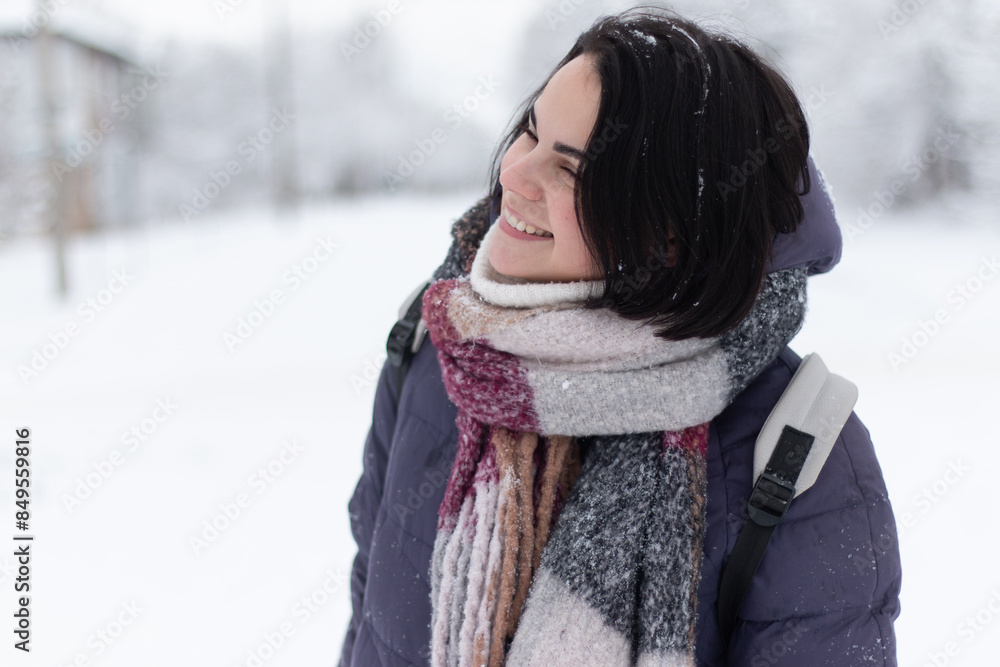 Young smiling beautiful woman wearing scarf outdoors during snowfall Young smiling beautiful woman wearing scarf outdoors during snowfall