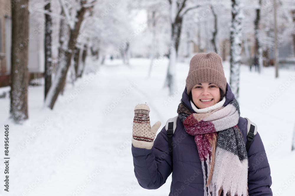 Obraz premium Young smiling beautiful woman wearing scarf outdoors during snowfall