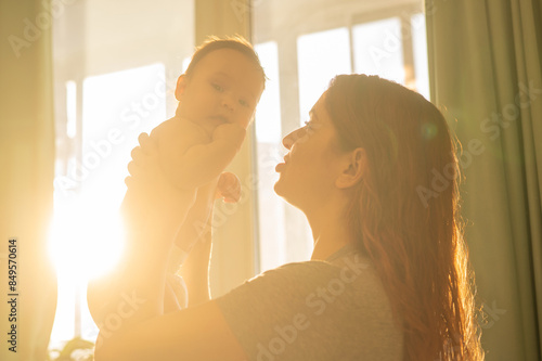 Caucasian woman gently lifts up her newborn son.  photo