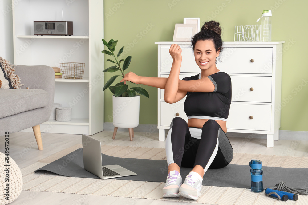 Sporty young African-American woman training on mat in living room Sporty young African-American woman training on mat in living room