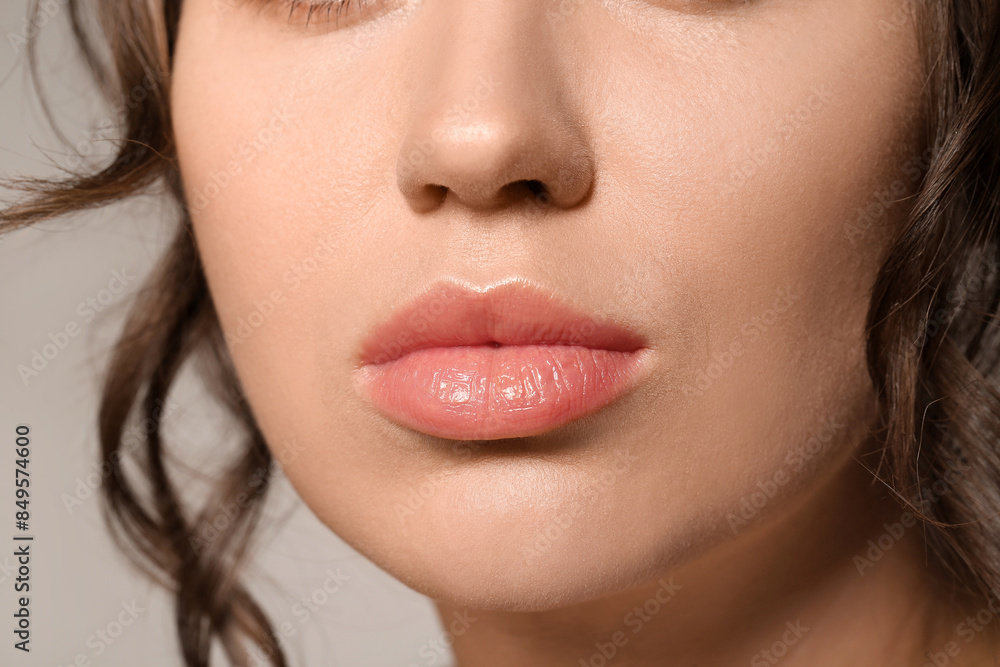 Beautiful young woman with nude lipstick on grey background, closeup Beautiful young woman with nude lipstick on grey background, closeup