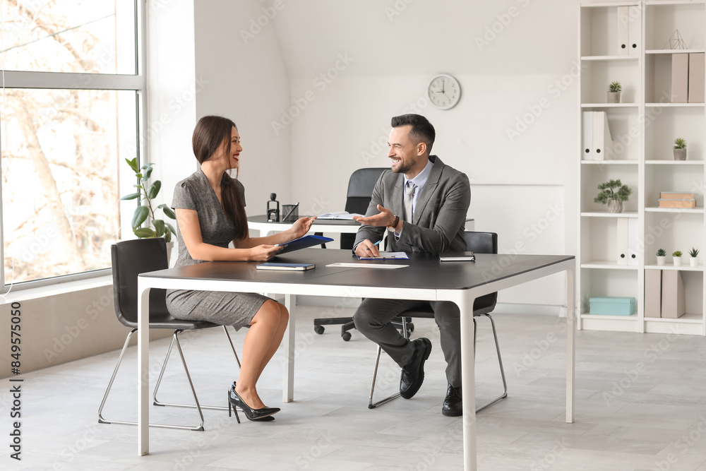 Human resources manager interviewing female applicant at table in office Human resources manager interviewing female applicant at table in office