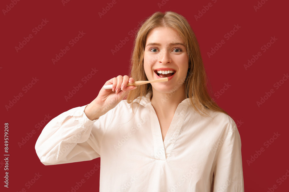 Young woman brushing her teeth on red background Young woman brushing her teeth on red background
