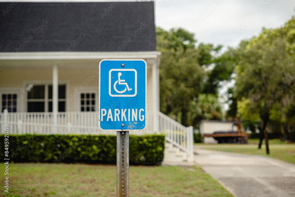 Blue Disabled PARKING blue sign, with traditional southern white building in the background. Blue Disabled PARKING blue sign, with traditional southern white building in the background.