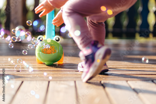 Tableau sur toile The legs of a child in front of a soap bubble toy blowing bubbles
