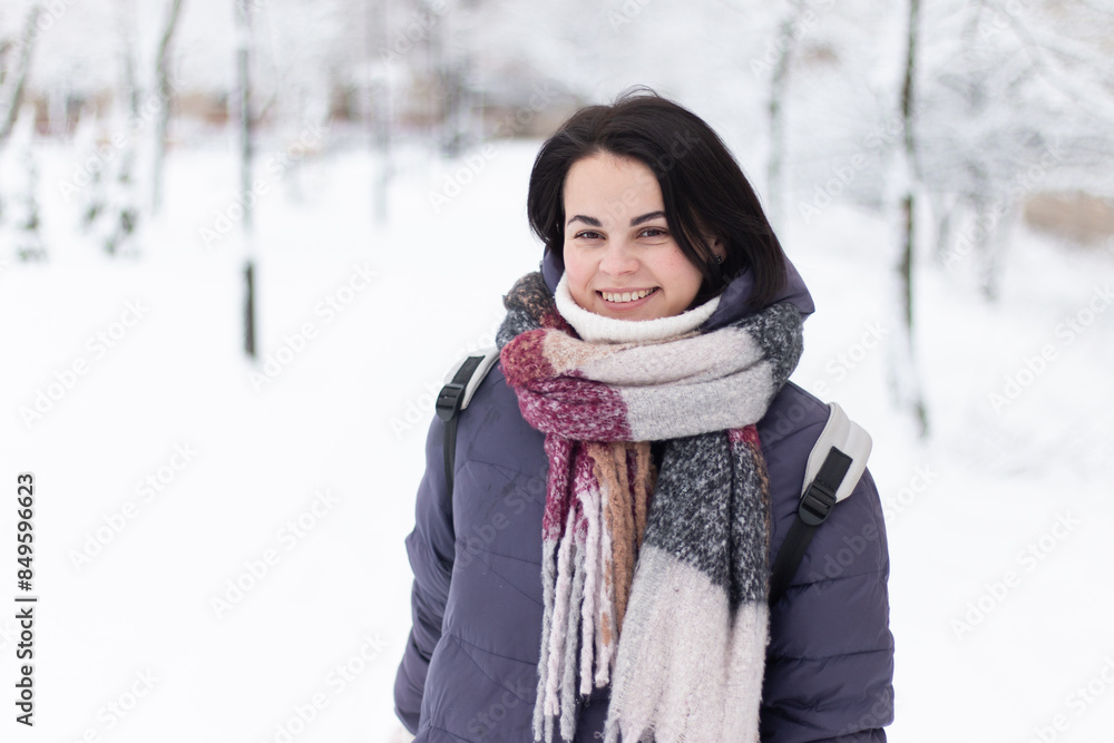 Young smiling beautiful woman wearing scarf outdoors during snowfall Young smiling beautiful woman wearing scarf outdoors during snowfall
