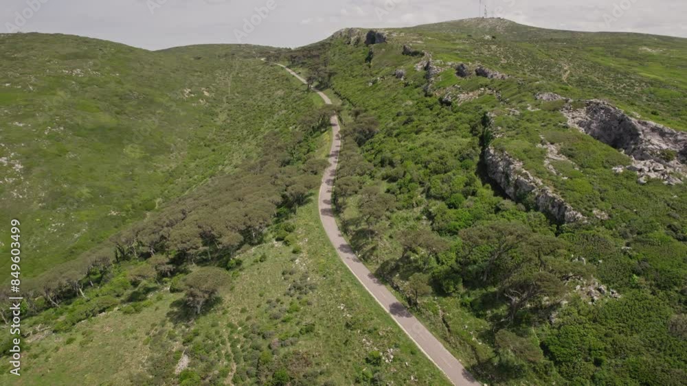 An above view captures motorcyclists navigating a winding road through lush, green mountainous terrain, offering a sense of adventure and freedom. An above view captures motorcyclists navigating a winding road through lush, green mountainous terrain, offering a sense of adventure and freedom.