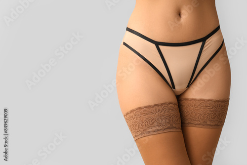 Bilde på lerret Beautiful woman wearing underwear and stockings on light background, closeup