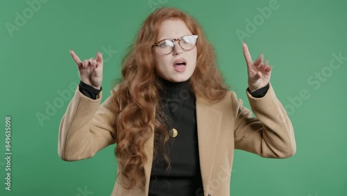 Irritated sarcastic businesswoman showing bla-bla gesture hands on green studio