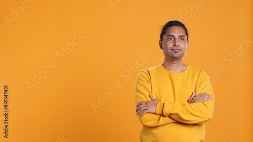 Portrait of cheerful friendly indian man smiling, looking pleased, isolated over yellow studio background. Happy expressive asian person grinning, feeling satisfied, camera B