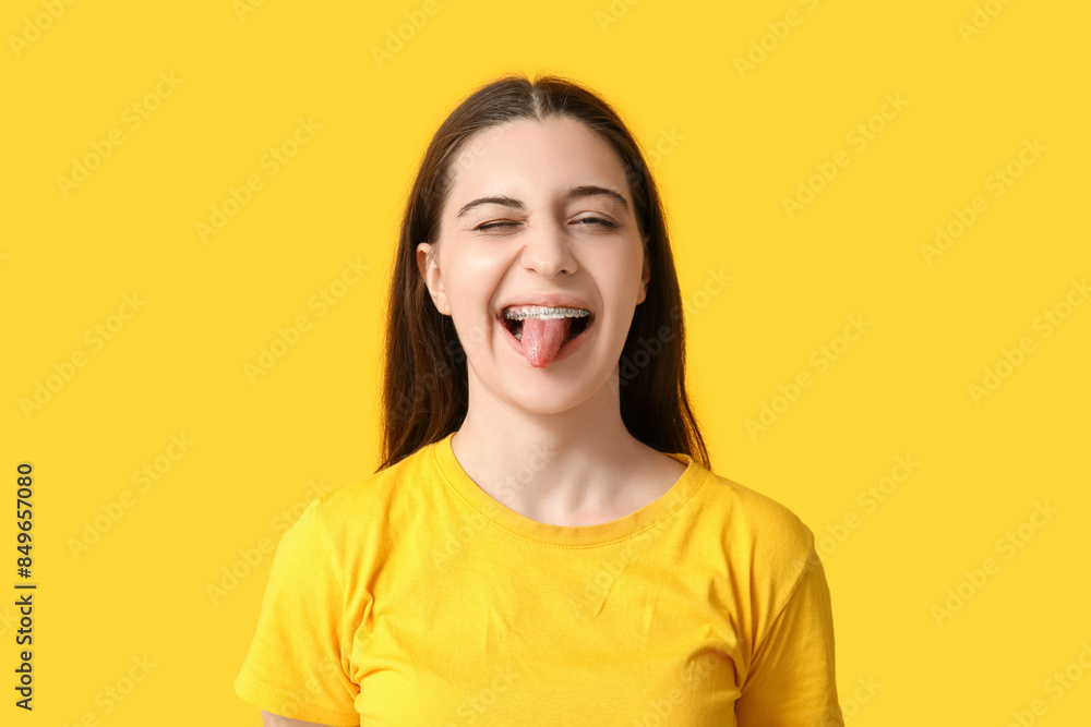 Happy young woman in stylish yellow t-shirt showing tongue on color background Happy young woman in stylish yellow t-shirt showing tongue on color background